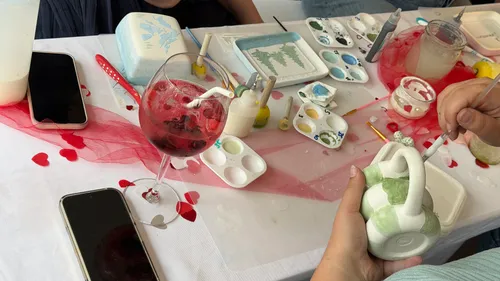 Hands painting pottery at decorated table.