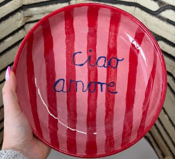 Hand hält rotgestreifte Schüssel mit Schrift.