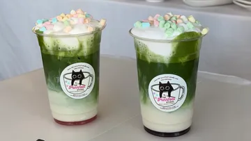 Zwei Matcha-Getränke mit Marshmallows auf Tisch.