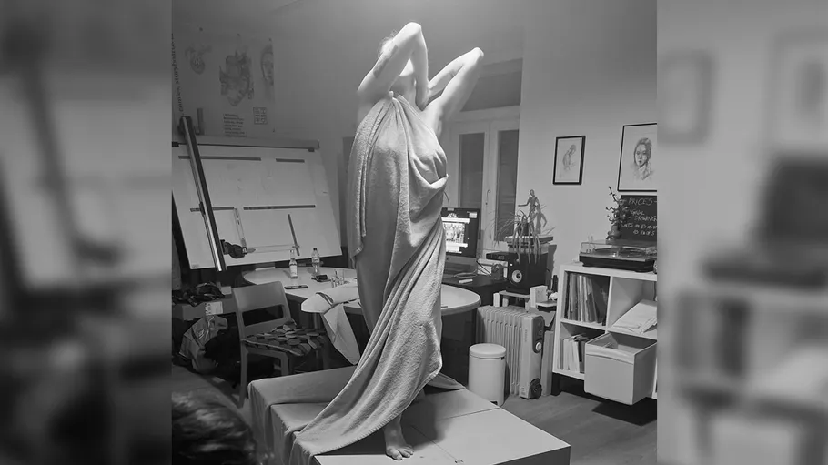 Person wrapped in fabric posing in art studio.