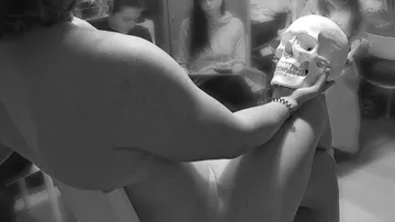 Nacktes Model mit Schädel in Kunstkursumgebung.