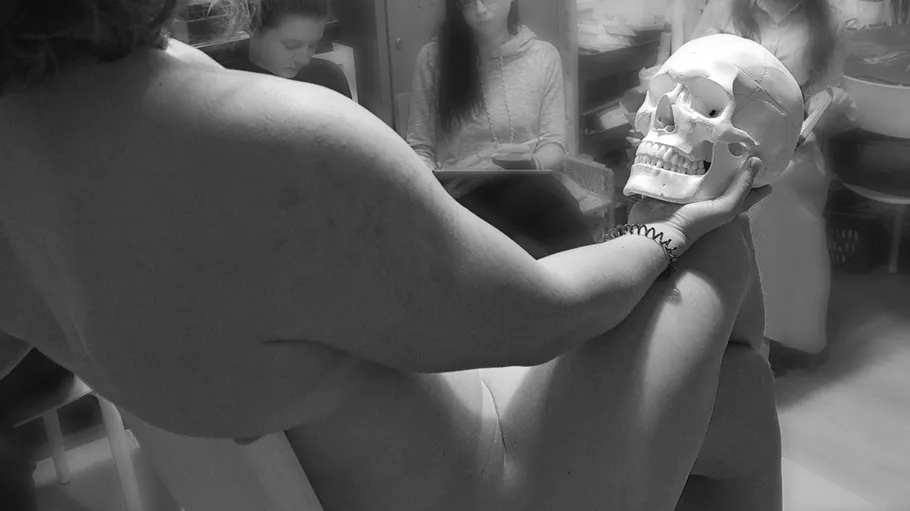 Nacktes Model mit Schädel in Kunstkursumgebung.