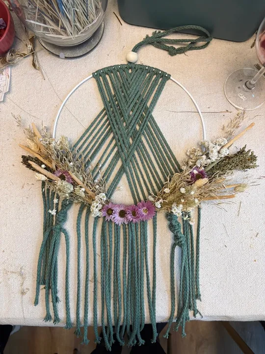 Makramee Wandbehang mit Trockenblumen, auf Tisch.