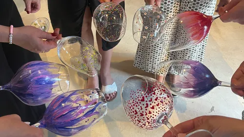 Hands hold decorated wine glasses indoors.