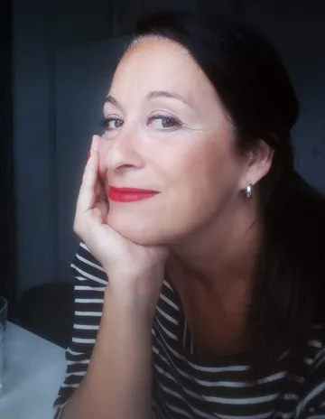 Person smiling, resting chin on hand, indoors.