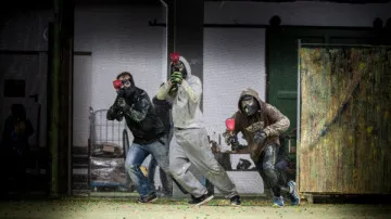 Three people playing paintball indoors.