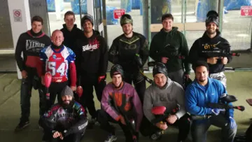 Group of people holding paintball guns indoors.