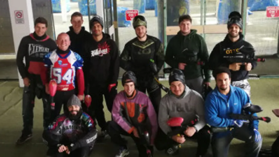 Group of people holding paintball guns indoors.
