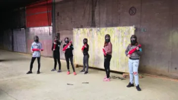 Personen halten Paintball-Waffen drinnen.