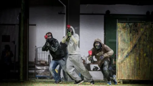 Drei Personen spielen Paintball drinnen.