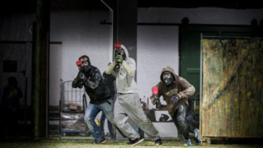 Drei Personen spielen Paintball drinnen.