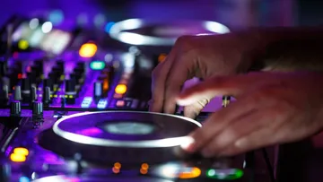 Hände justieren DJ-Ausrüstung im Club.