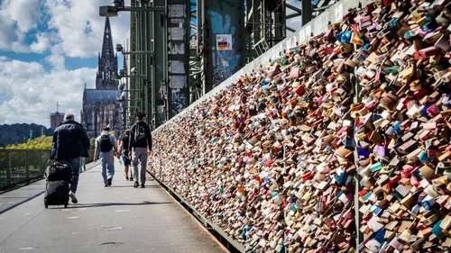 Pedestrians walking on bridge with love locks.