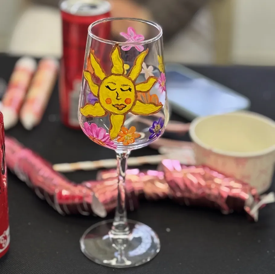 Wine glass painted with sun and flowers.