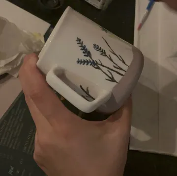 Hand bemalt eine Tasse mit Blumenmotiv.
