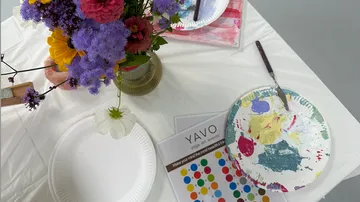 Colorful flowers and paints on a table.