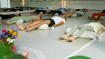People lying in yoga class studio.