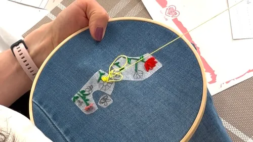 Embroidery hoop with floral design on jeans.