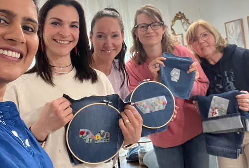 Fünf Frauen zeigen Stickerei auf Jeansstoff.