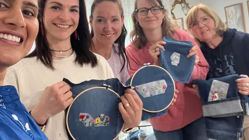 Five women display embroidery on denim.