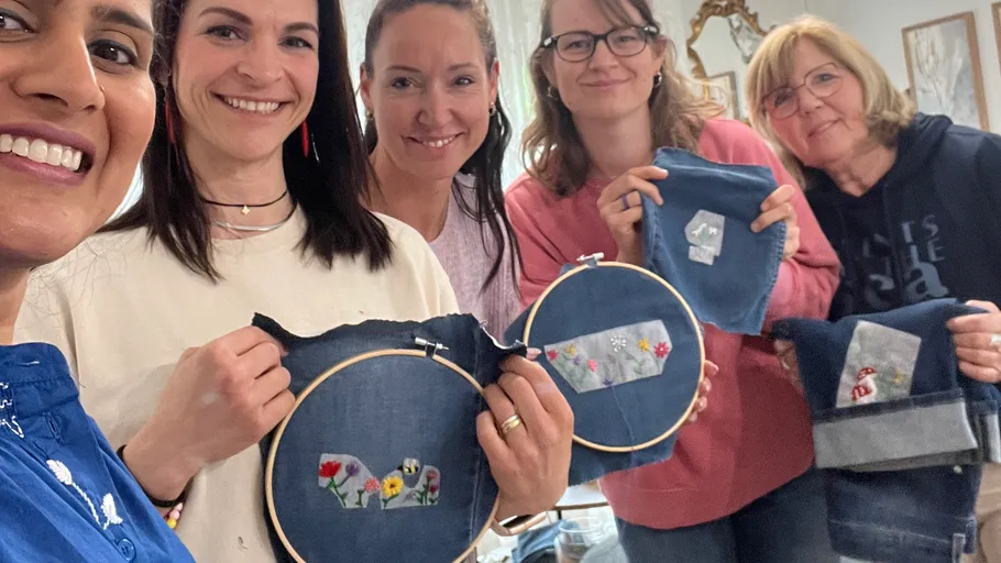 Fünf Frauen zeigen Stickerei auf Jeansstoff.