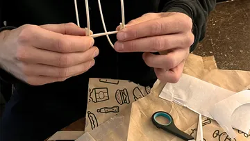 Hands crafting with paper and sticks.