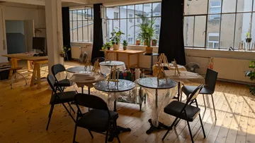 Kunststudio mit Tischen und Staffeleien.