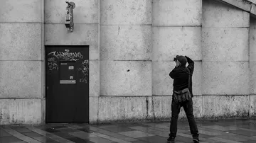 Person fotografiert Gebäude mit Kameraskulptur.
