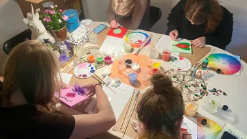 People painting at a craft table.