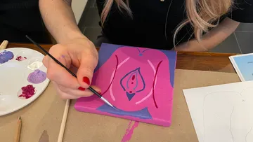 Person painting abstract art on small canvas.