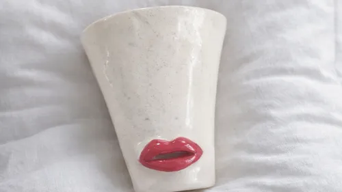Weiße Keramiktasse mit roten Lippen.