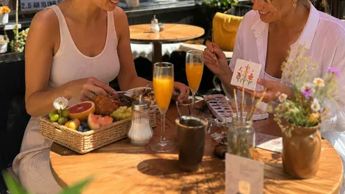 Two women enjoying brunch in outdoor cafe.