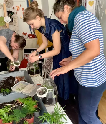 Menschen gestalten Terrarien an einem Tisch drinnen.