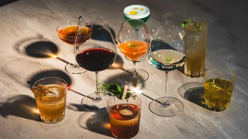 Acht verschiedene Cocktails auf einem Tisch.
