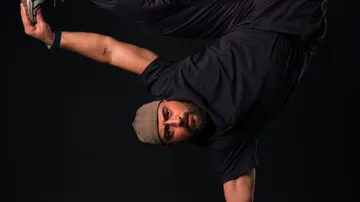 Mann im Handstand, dunkler Hintergrund.