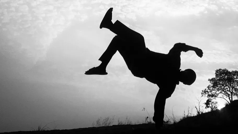 Silhouette of person breakdancing outdoors.
