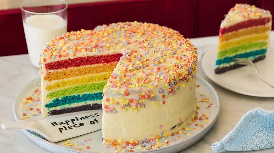 Colorful layered cake with sprinkles on table.
