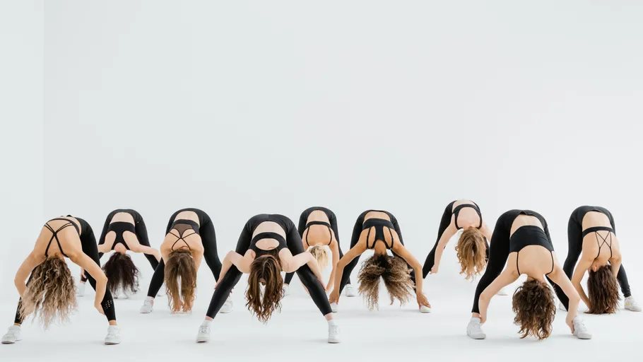 Group of dancers bending forward in studio.