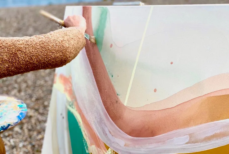Person painting abstract art on large canvas outdoors.