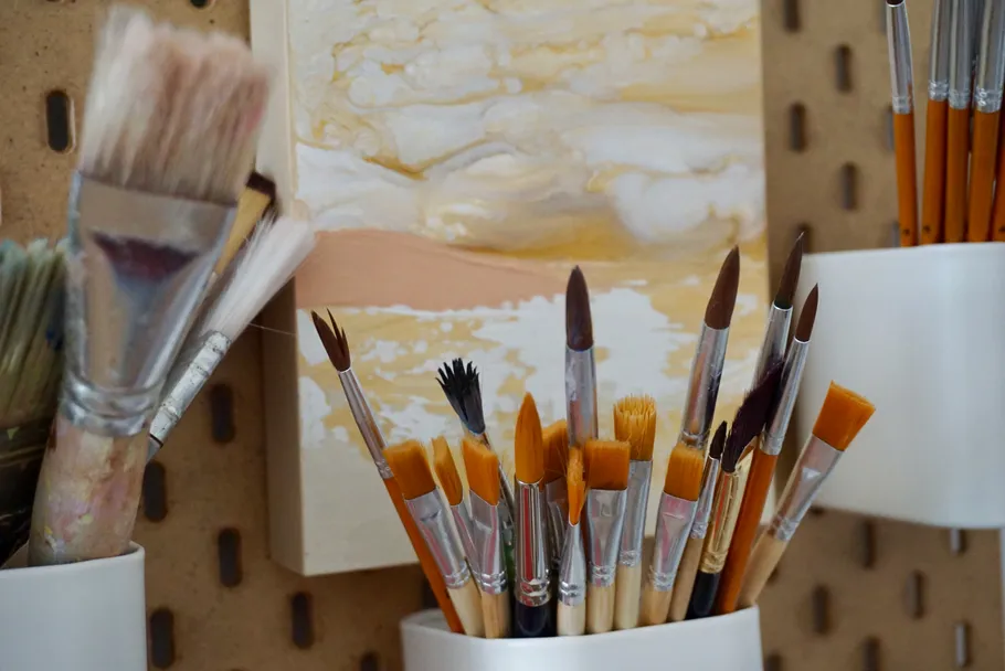 Paintbrushes in holders on pegboard wall.