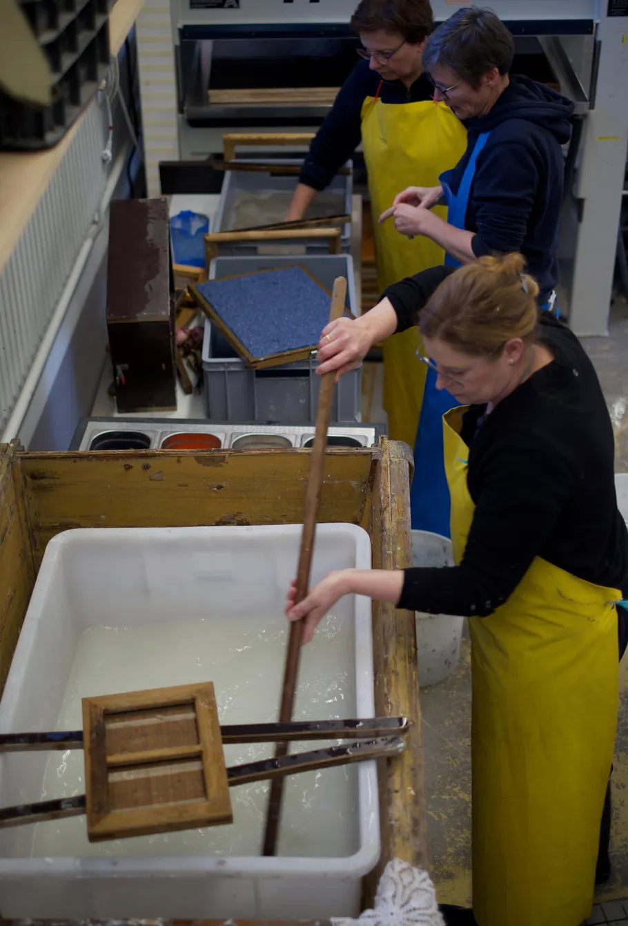 People making paper manually in workshop.