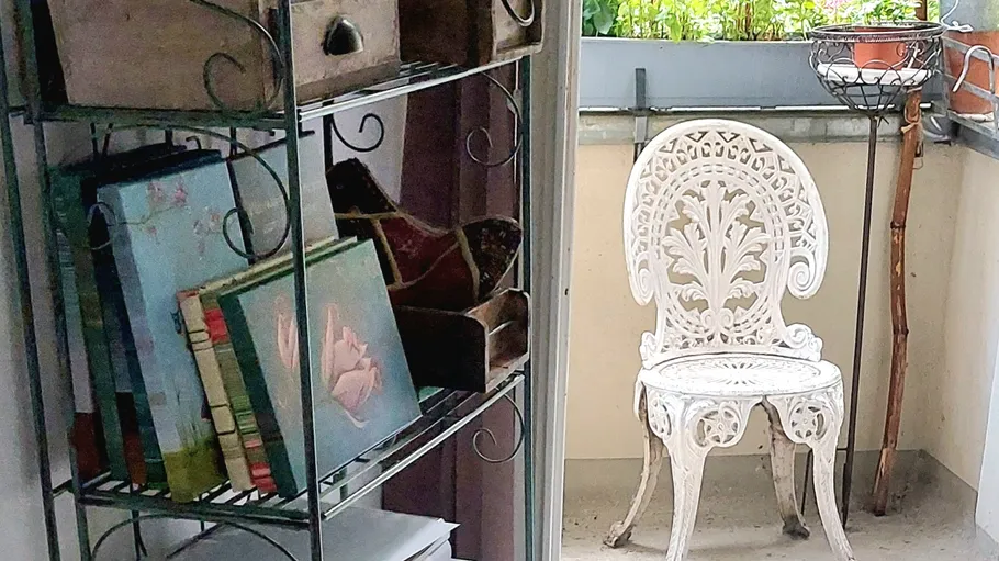 White ornate chair on small balcony.