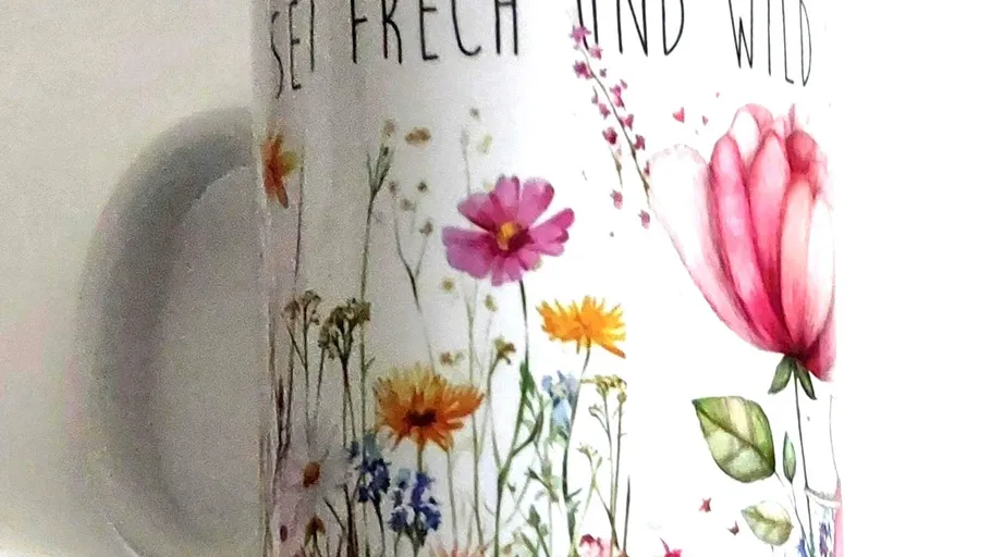 Mug with colorful floral pattern and text.