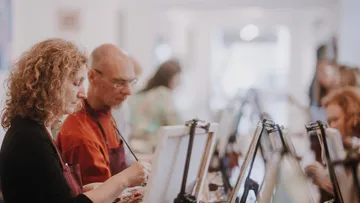 Menschen malen auf Leinwänden in einem Studio.
