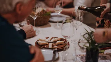Personen essen Käse und gießen Wein.