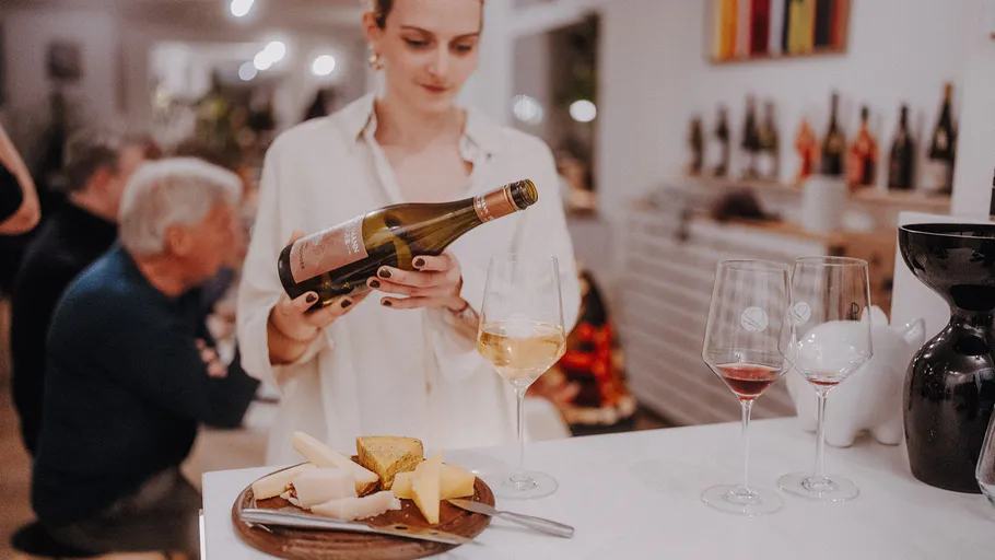 Woman pouring wine at home gathering.