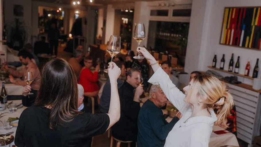 Two women toasting in a lively restaurant.