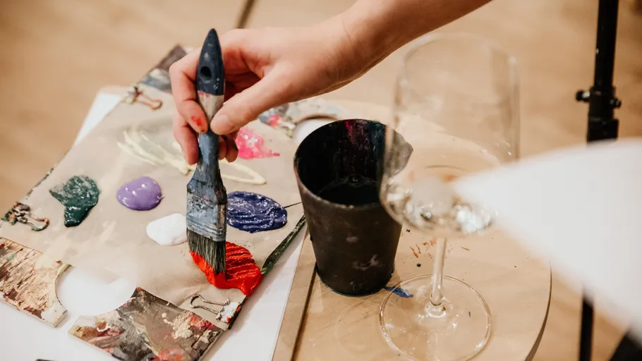 Hand painting on canvas, wine glass nearby.