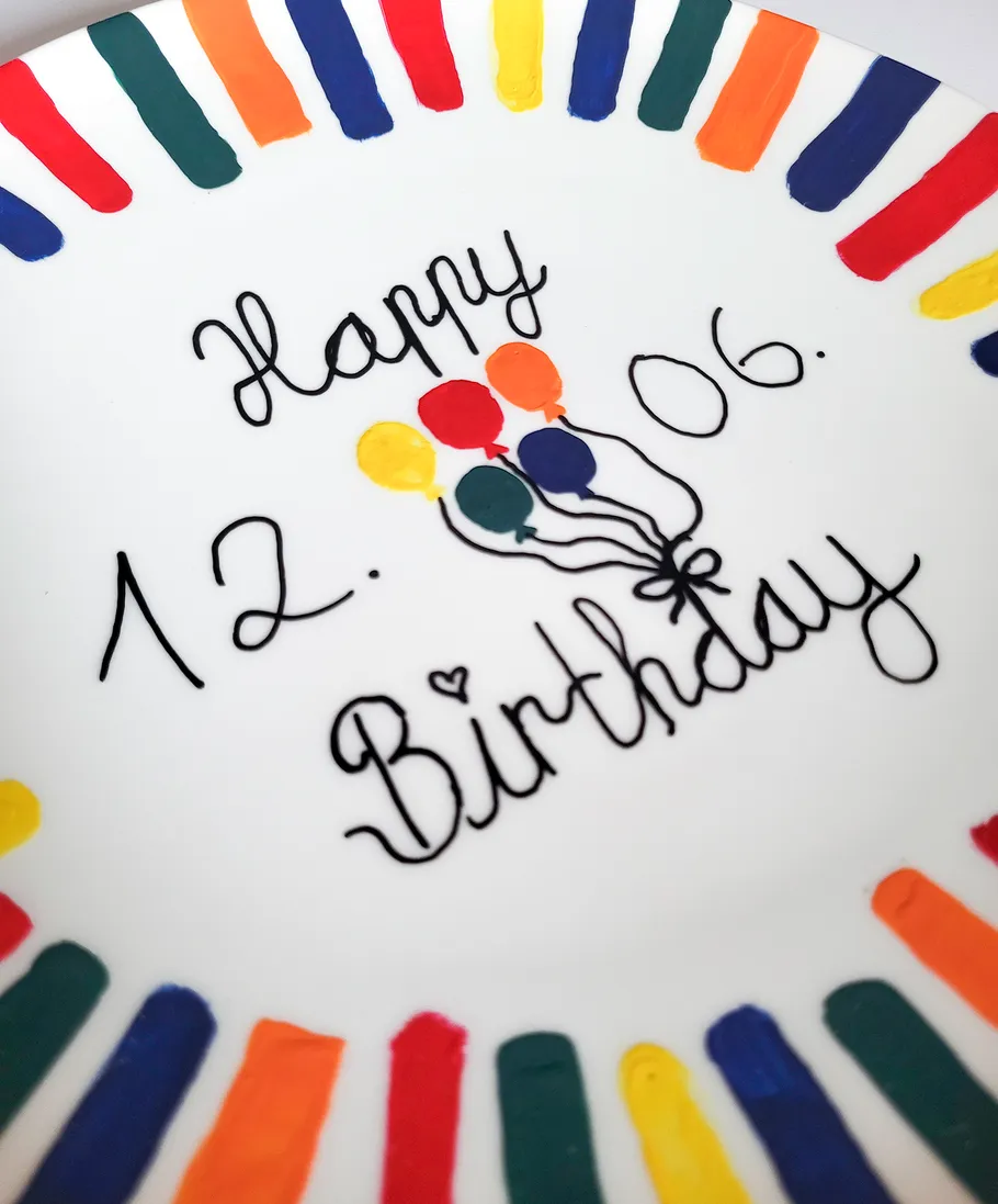 White plate with colorful stripes, birthday text.