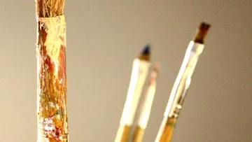 Paintbrushes standing upright against beige background.